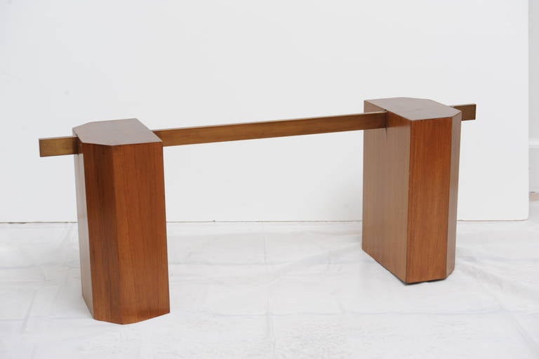 This unusual Danish, mid-century modern coffee table is made of two beveled solid teak bases connected with a brass rectangular rod. The glass top is beveled and angled at the corners mirroring the beveled bases.