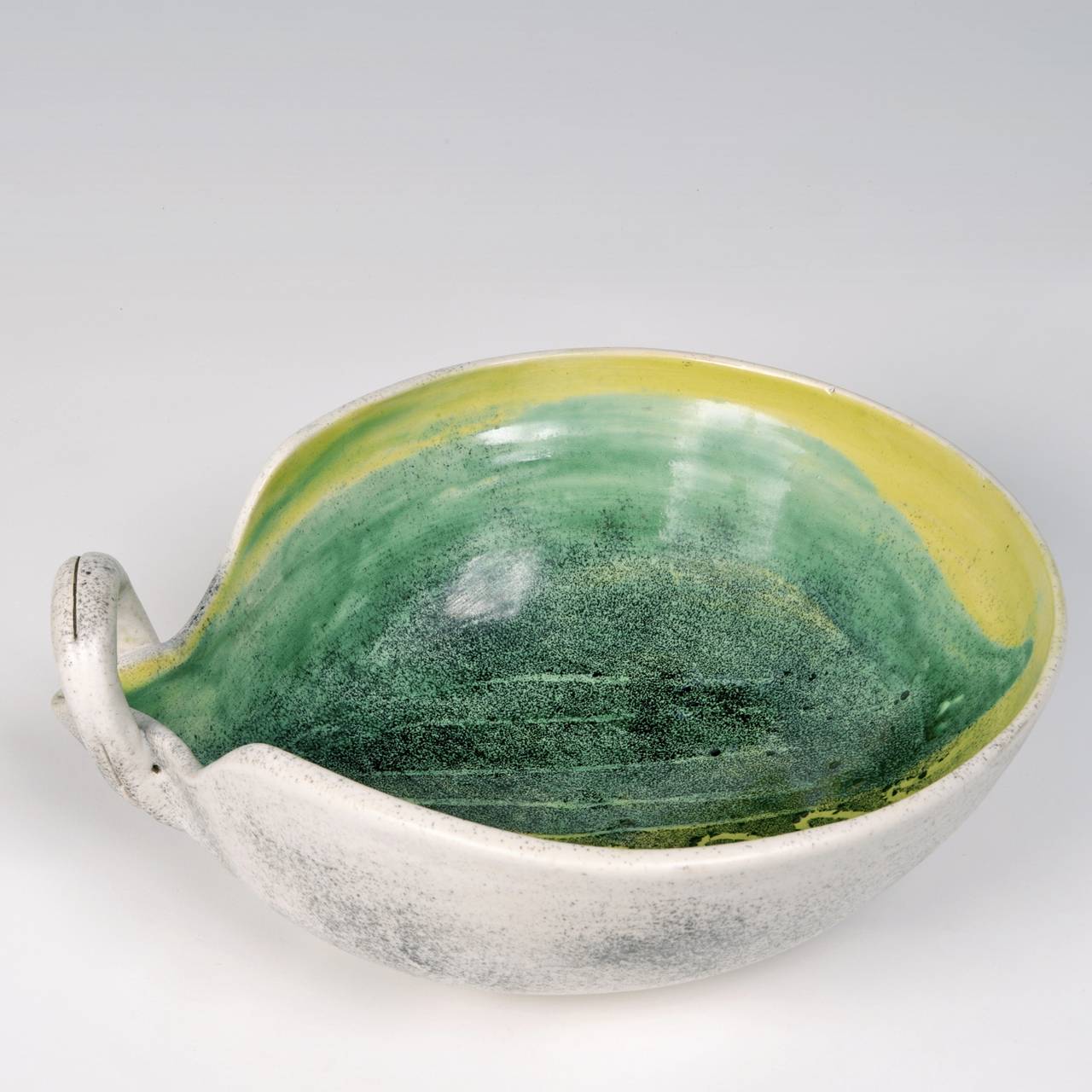 Modeled earthenware bowl, glazed back in white flecked with dark grey, and decorated with a vegetal figure over-glazed in shiny shades of green.

By the French artist ceramicist : Mado Jolain (signed M J on the bottom).