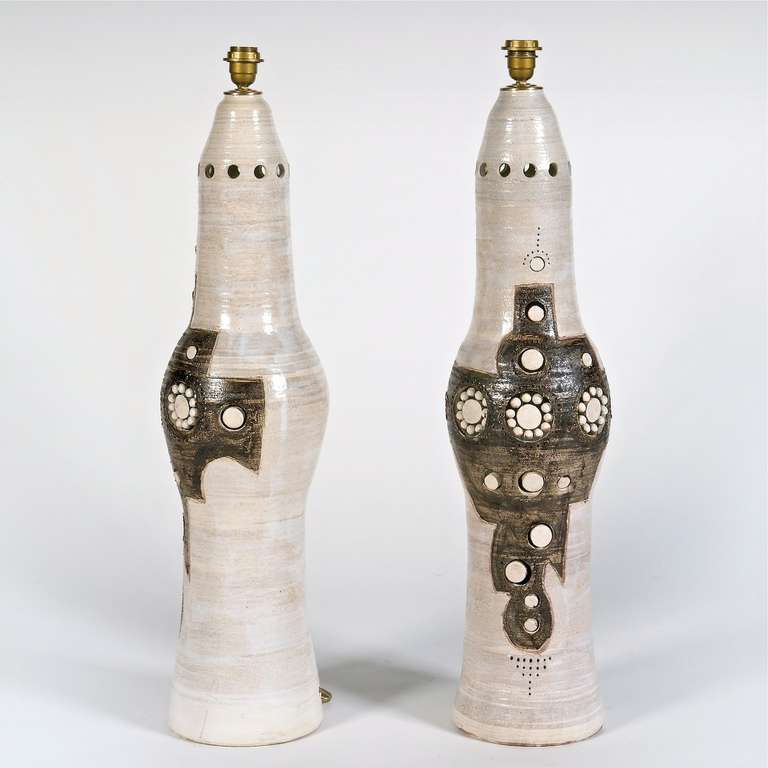 Large pair of floor-lamps in grogged clay with beige and brown glaze and slip, decorated with stylized perforations and unglazed white ceramic pearls or pastilles. 
Irradiant light two ways inside the lamp-stands and up. 

A beautiful and rare