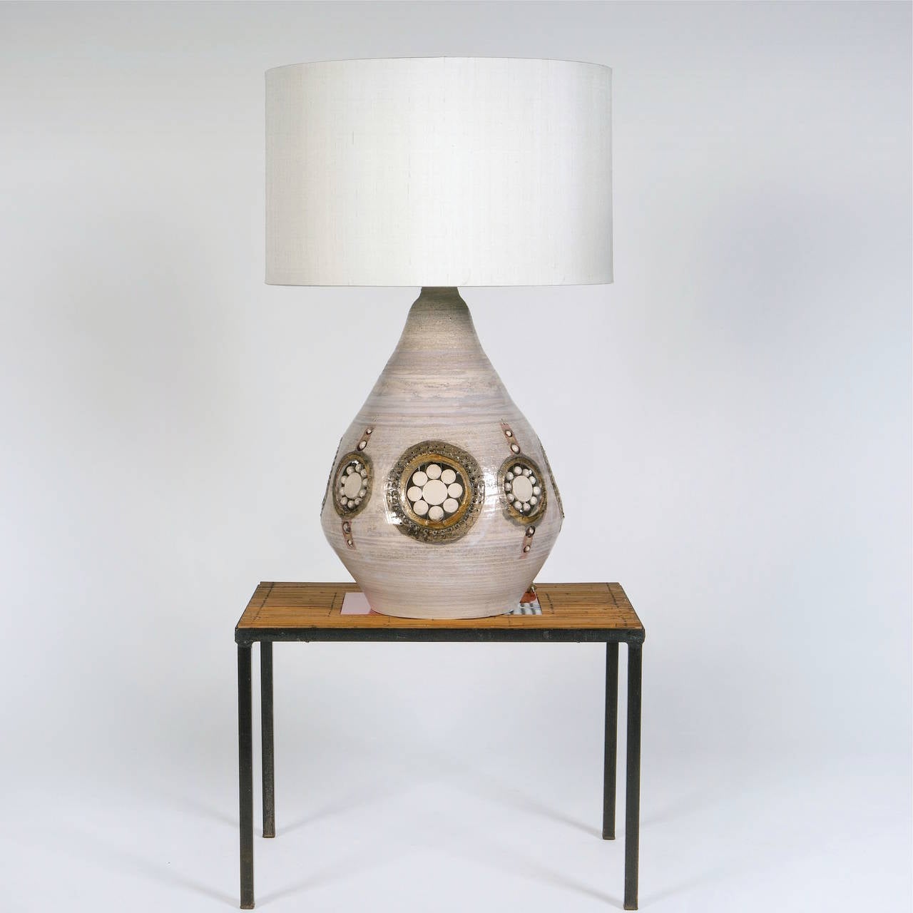 Important lamp base, grogged clay, shiny beige slightly pinkish ground glaze and decorated with stylized perforations and glazed ceramic pearls and pastilles. 
Irradiant light two ways inside the lamp-base and up. 

A beautiful pottery piece modeled