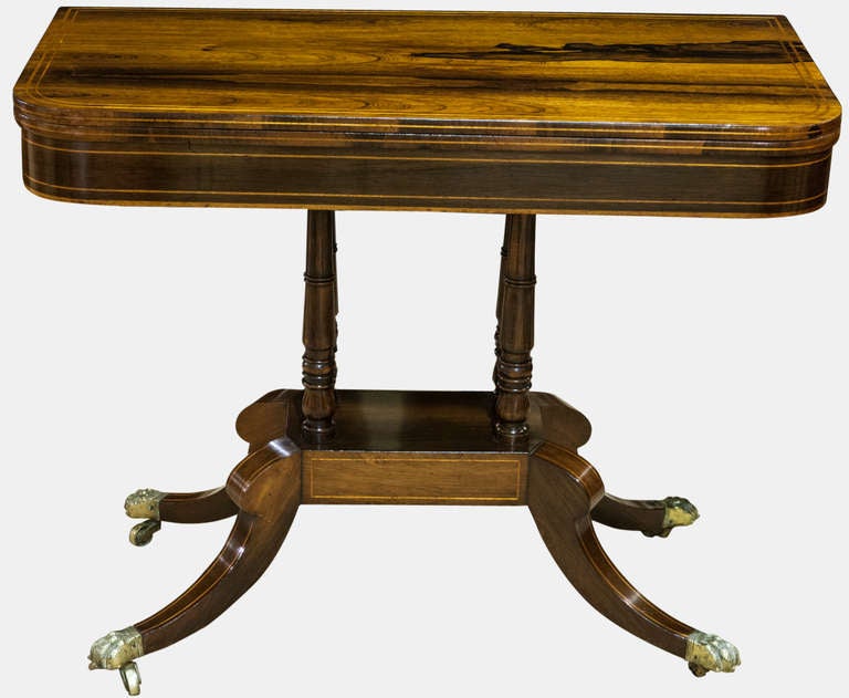 A Regency Rosewood And Boxwood Inlaid Card Table On Four Turned Supports, Outswept Legs And Original Brass Hairy Paw Feet On Castors. Baize Recently Replaced.