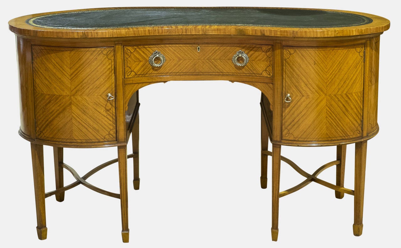 A late Victorian satinwood kidney-shaped writing desk or dressing table. With quarter veneered door panels on square tapering legs and spade feet.