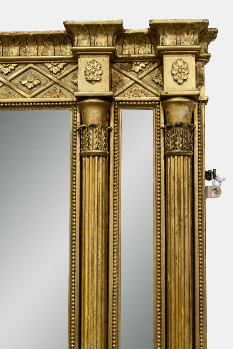 A Regency gilt Gesso overmantel mirror of small proportions with double outset reeded side column with corinthian capitals, enclosing bevelled side slips and a leafwork moulded cornice above a hatched flower head frieze and a large rectangular