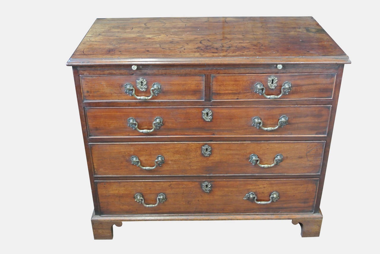 A Handsome And Well Patinated George II Oak Lined Mahogany Chest Of Drawers With Brushing Slide And Two Short, Three Long Drawers With Original Brassware, Standing On Original Bracket Feet