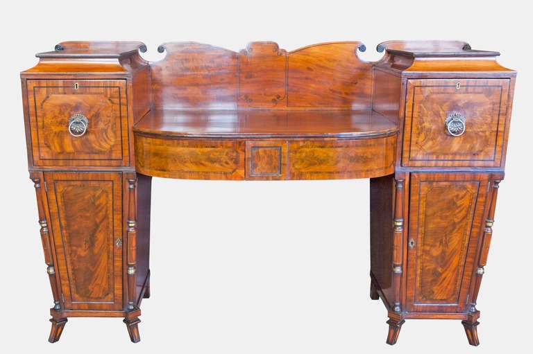 A beautiful Regency inlaid and cross banded flame mahogany sideboard with original brass 'clam shell' handles, with one deep drawer and one cellarette drawer over two cupboards on original splayed feet.
