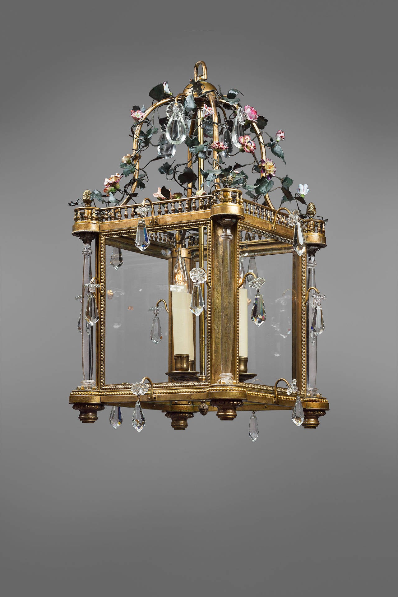Exceptional bronze lantern with crystals,
France, mid-19th century.
Painted iron and porcelain floral ornaments.
Four glass columns on the edges.
Three lights in the center.