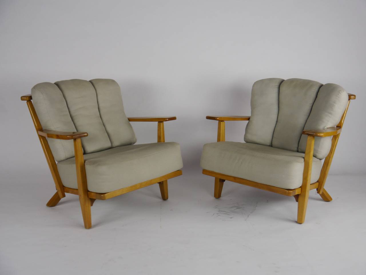 Unusual lounge chairs by Cushman, having Mid-Century styling, maple frames, original loose cushion upholstery and paddle arms.