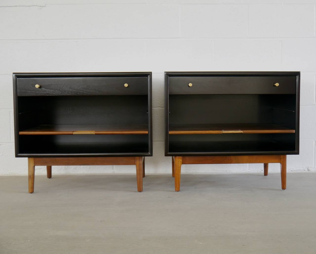Night stands in walnut by Kipp Stewart for Drexel. These large nightstands have drawers and an adjustable sliding shelf with raffia handles. The pulls are solid machined brass. We borrowed the finish from Dunbar pieces of the period, the cases done