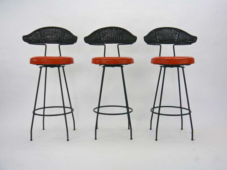 Five stools, by Maurizio Tempestini for Salterini. Each having a swivel seat, rod iron frame and woven curved backrest. Each labeled 