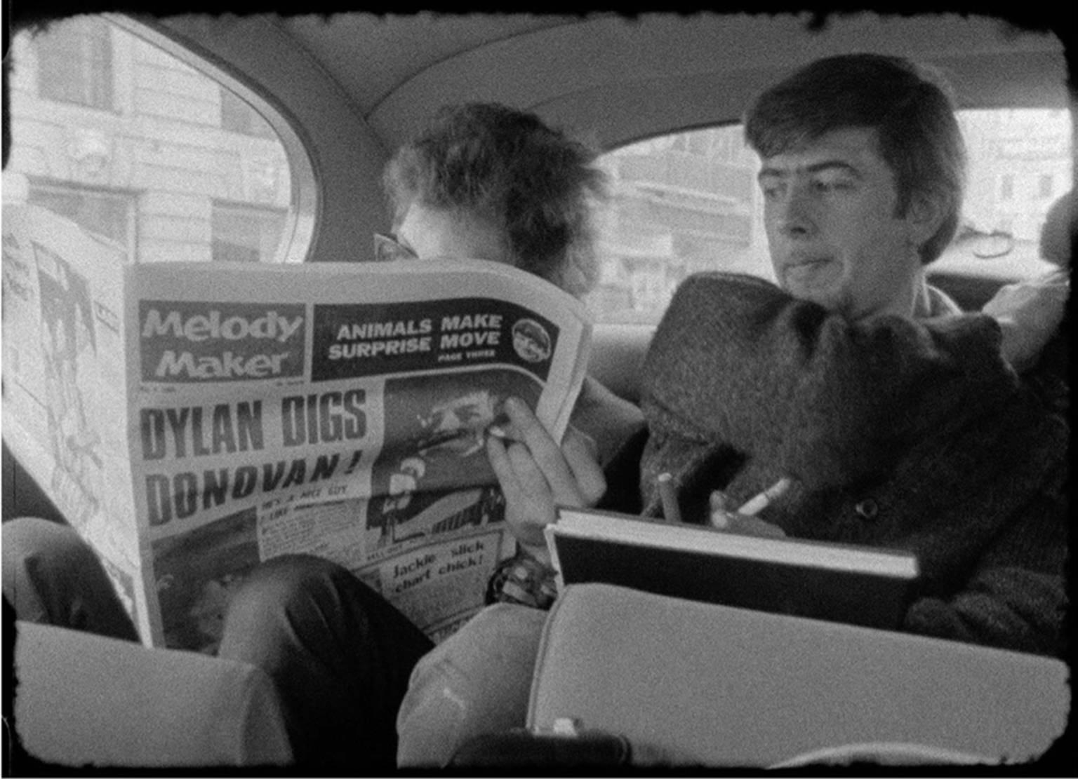 D.A. Pennebaker Black and White Photograph - Bob Dylan reading Melody Maker with John Mayall looking on London 1965 
