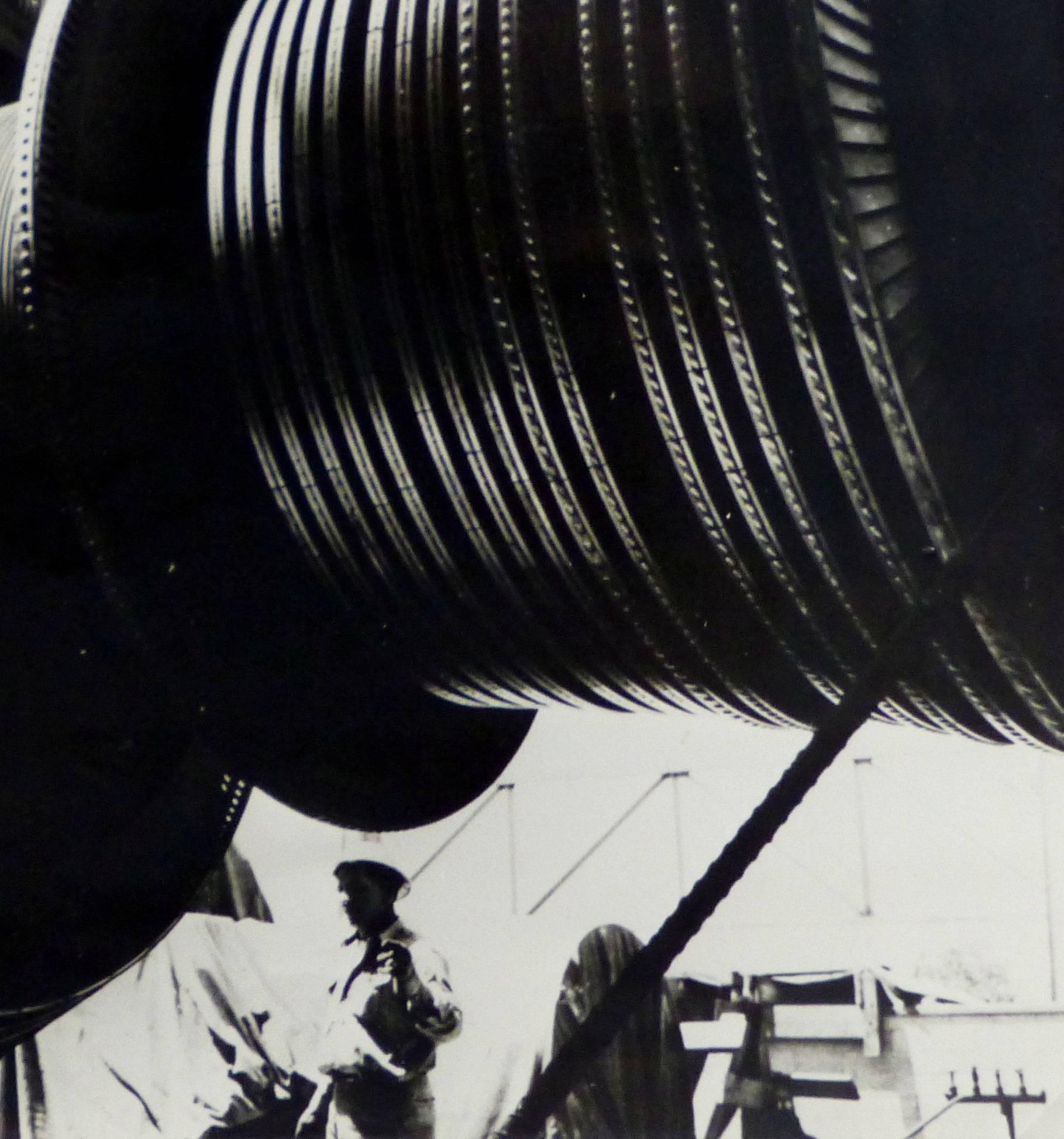 Vintage silver gelatin photograph of a large rocket booster with engineers looking on in the background, circa 1950. 

Original artwork on paper displayed on a white mat with a gold border. Archival plastic sleeve and Certificate of Authenticity