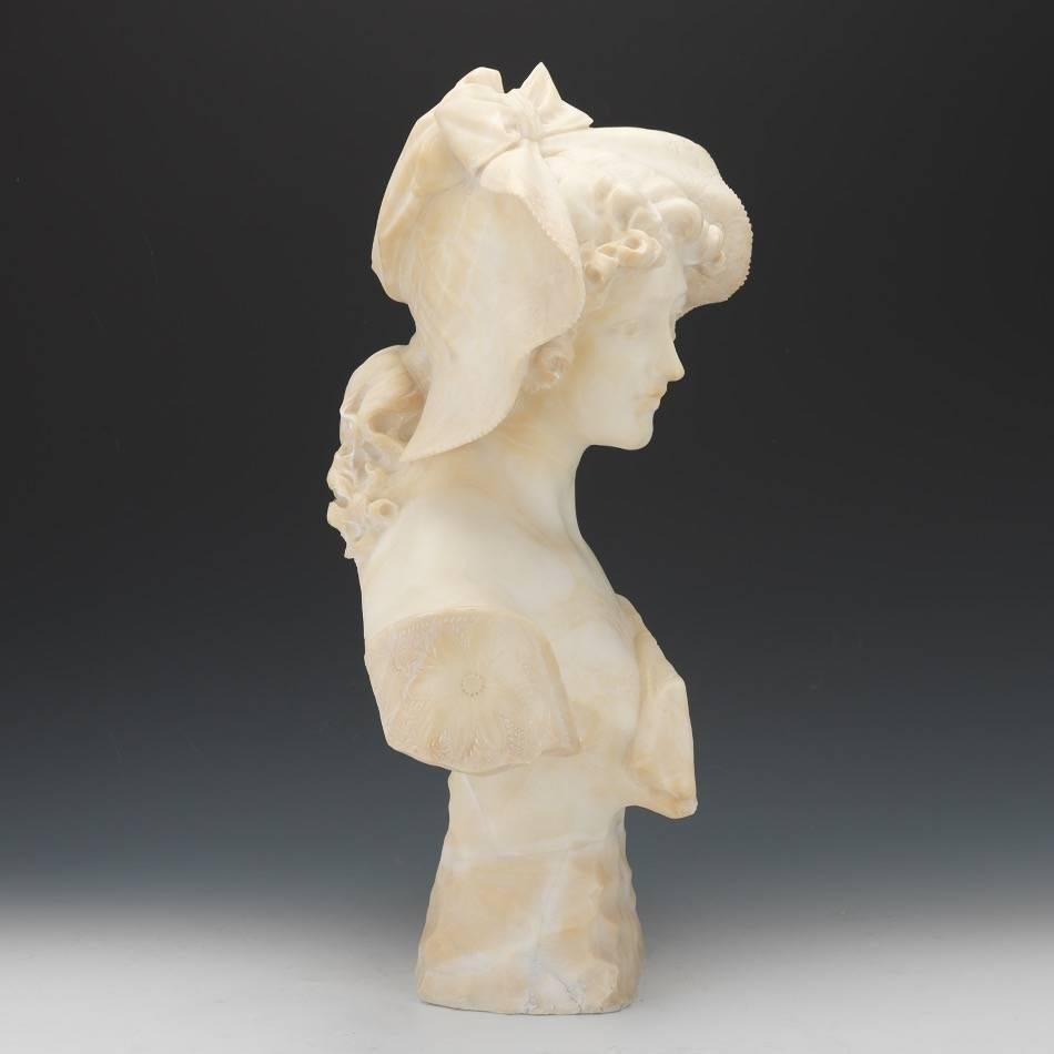 An original unsigned carved alabaster bust supported by a carved base. A young lady with a bonnet, Paris School, France, c. 1880-90. Some light handling wear, wear consistent with age: Very Good condition. This is an absolutely beautiful bust.