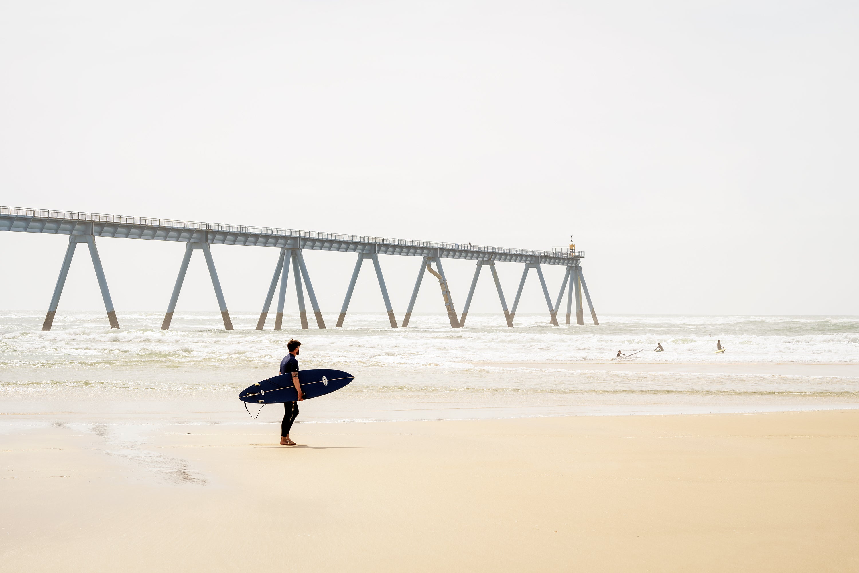 Wave Watcher, France – Minimalist Colour Fine Art Photograph of Surfer on Beach