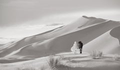 Cloaked Figure Walking Beside Horse Through Desert Dunes