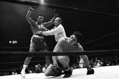  Muhammad Ali victorieux, renversé par l'arbitre Mark Conn après avoir frappé un match
