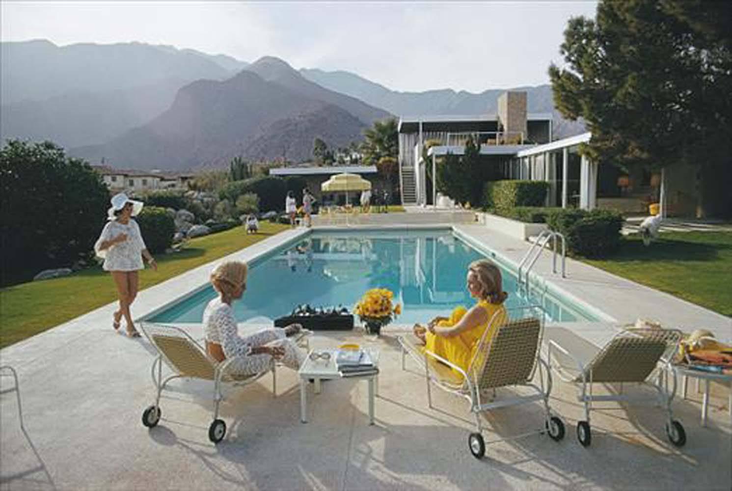 1970: A desert house in Palm Springs designed by Richard Neutra for Edgar Kaufman. Lita Baron approaches Nelda Linsk, right, wife of art dealer Joseph Linsk who is talking to a friend, Helen Dzo Dzo. This is Aarons's recently released sister image