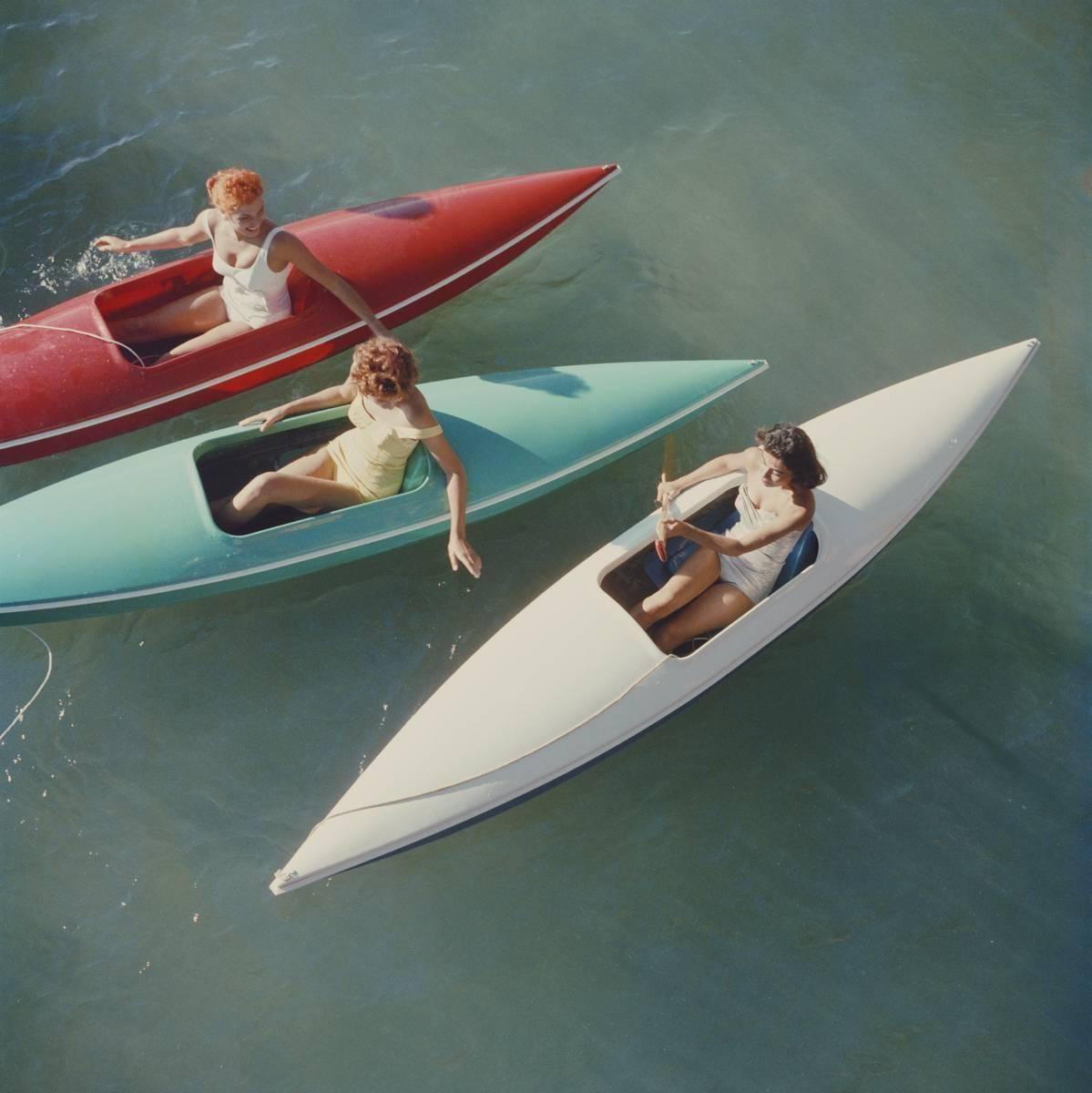 1959: Young women canoeing on the Nevada side of Lake Tahoe, a large freshwater lake in the Sierra Nevada Mountains, straddling the border of California and Nevada. Three young woman are pictured in their red, turquoise and white canoes in the