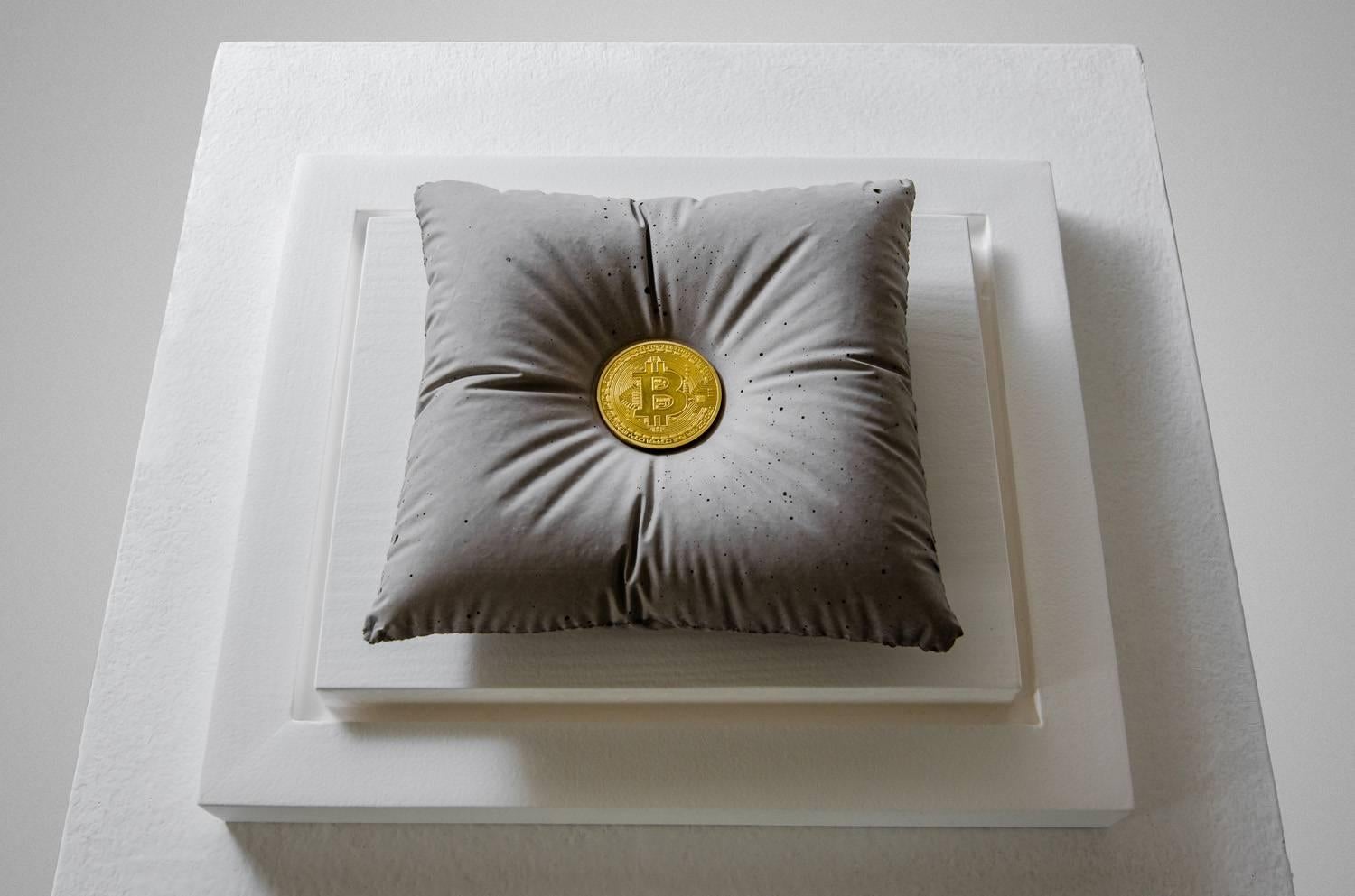 ONE BITCOIN
Concrete Pillow holding the weight of a Bitcoin. Sculpture enclosed in a glass urn.

Concept:
The sculpture is an ode to the blockchain revolution, headed by Bitcoin. An altar to innovation and to the new digital assets that no