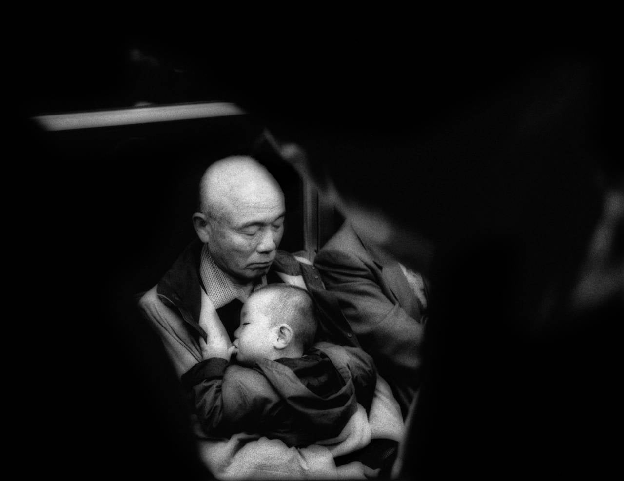 Sleeping man cradles sleeping child on subway, Tokyo, Japan