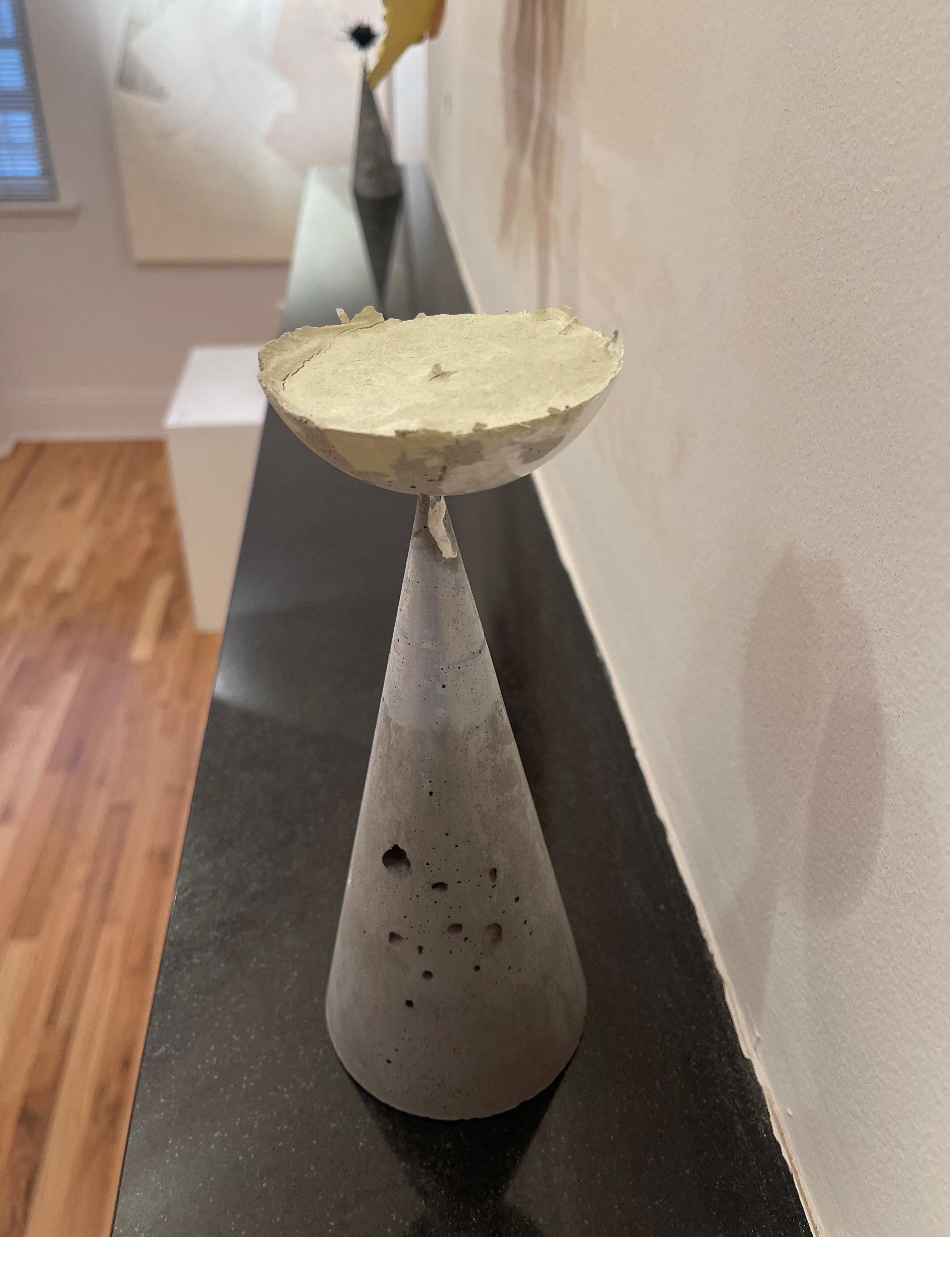 Moon Flower (2019) est une petite sculpture abstraite contemporaine, présentant un cône en béton, avec des détails altérés pour créer un effet robuste. Un prisme en forme de demi-lune se trouve en équilibre sur la pointe du prisme rectangulaire,