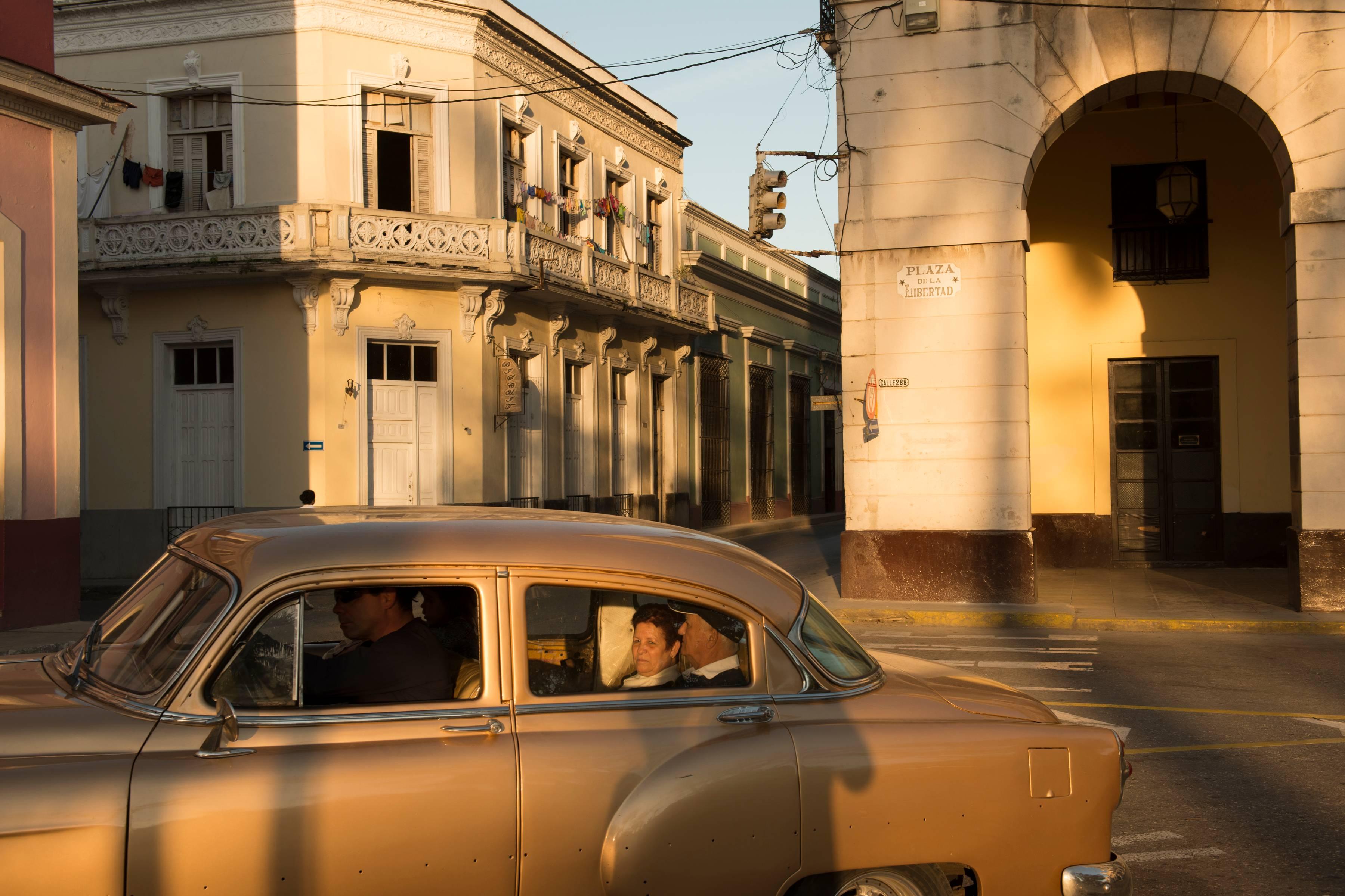 Cuba 4, Vintage Car, Travel, Gold, Cityscape, Architecture, Cuba, Color Photo - Photograph by John Conn