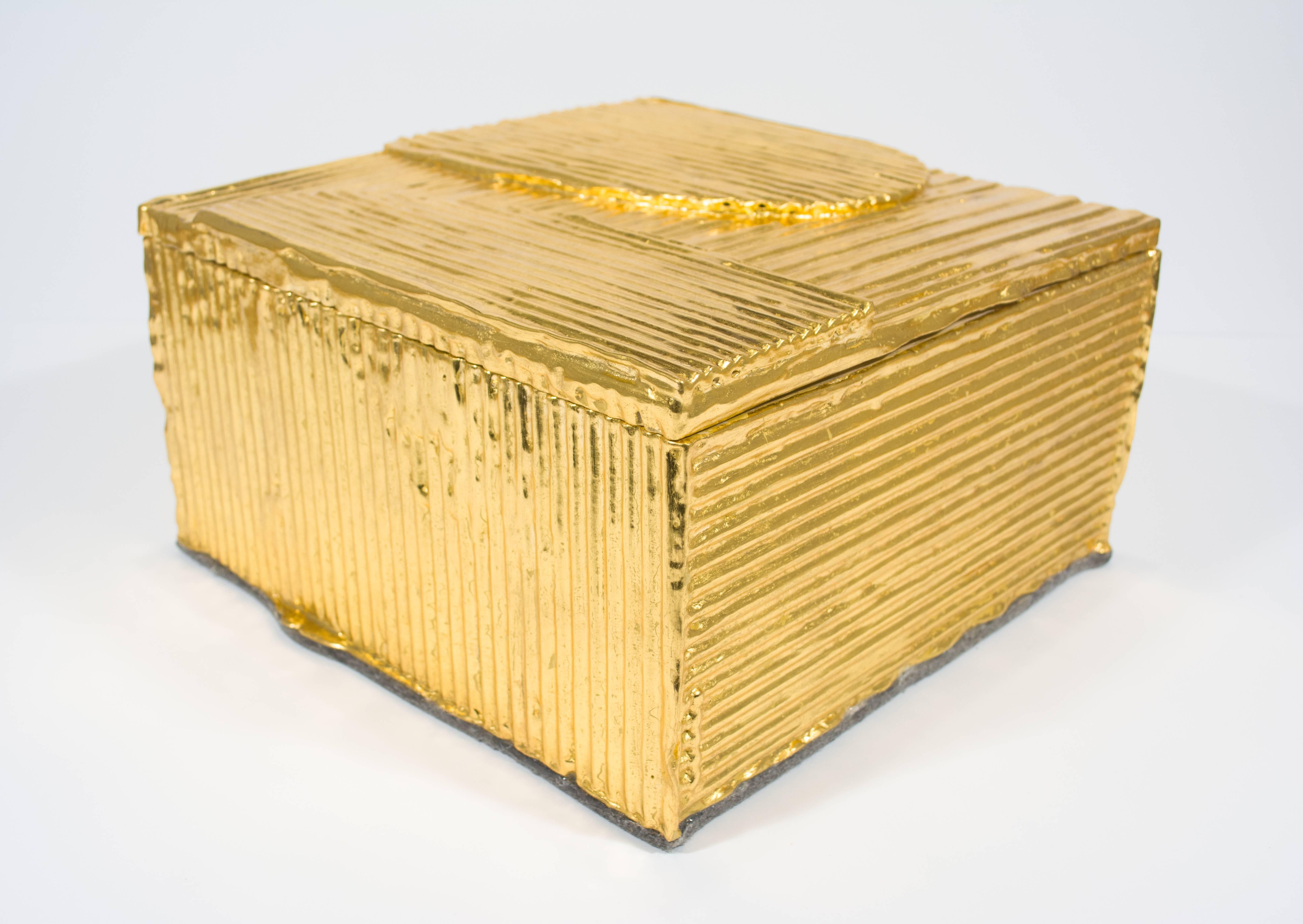 This functional box by Nancy Lorenz features a pawlonia box traditionally used for Japanese tea service. Attached to the outside are layers of cardboard, that Lorenz has gessoed and then covered in gold leaf. 

Nancy Lorenz earned a BFA in Painting