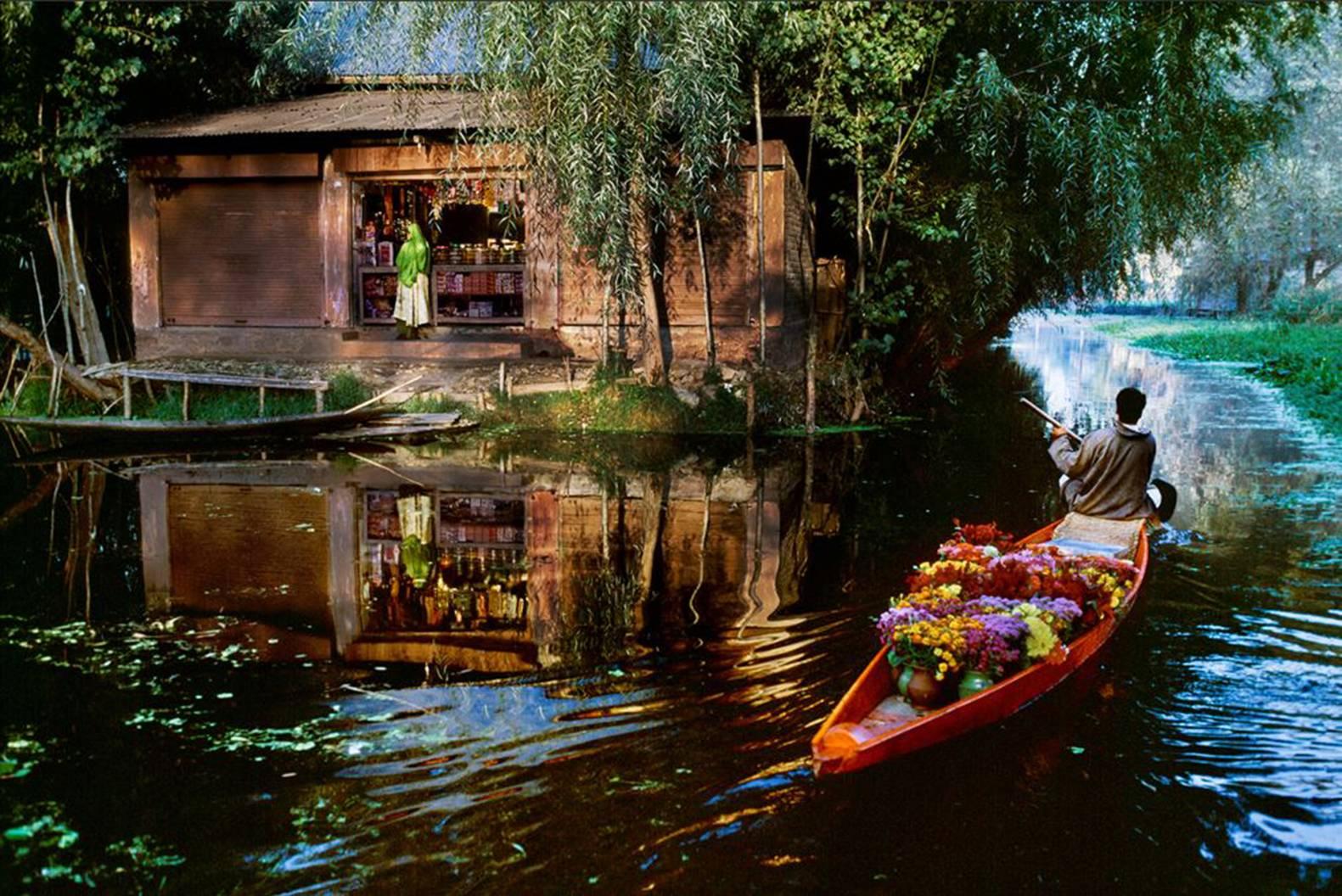 Color Photograph di Steve McCurry - Venditore di fiori sul lago Dal