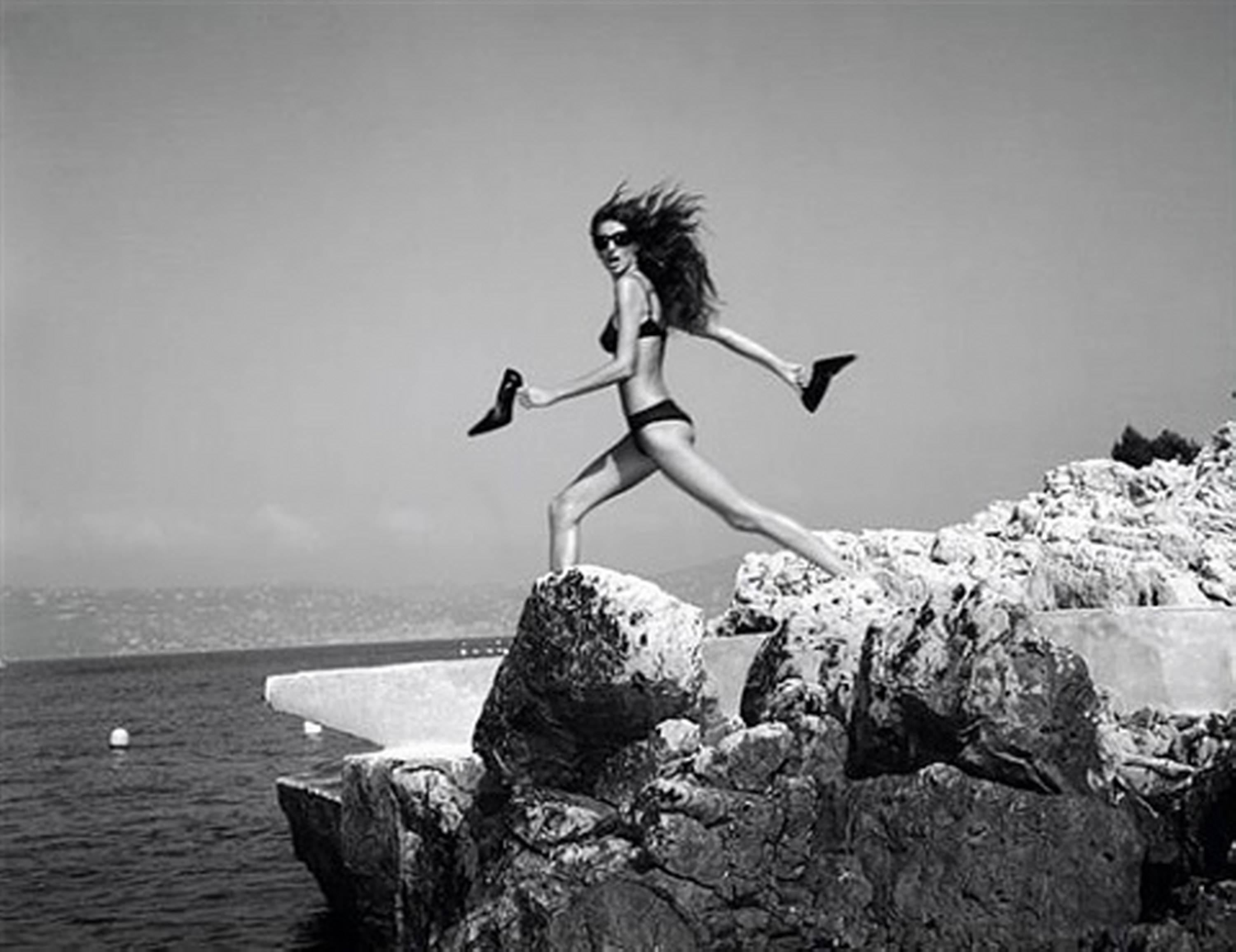 Michel Comte Black and White Photograph - Supermodel Gisele Bündchen in black bikini on rocks by the sea near Cannes 
