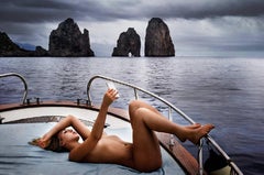 Capri Selfie - blonde naked woman on a boat, lying on her back, making a photo