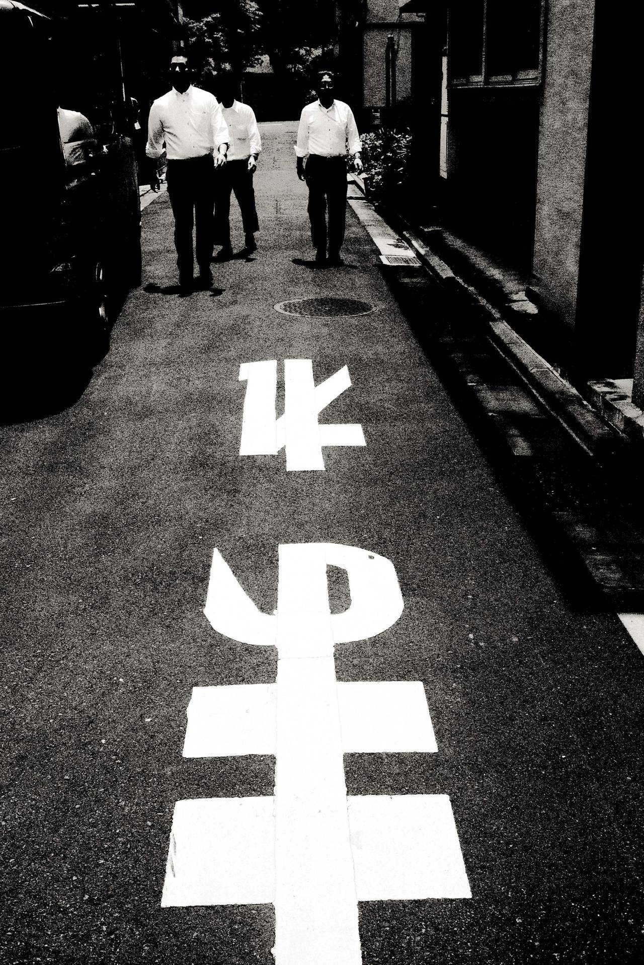 Andreas H. Bitesnich Still-Life Photograph – Drei Männer beim Spaziergang, Tokio – auf den Straßen in Japan, mit darauf gemalten Schildern