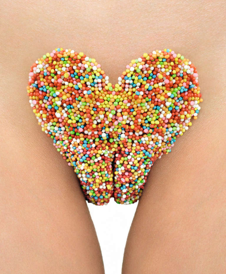 Hundreds & Thousands - Candies in shape of a heart are placed on a female nude