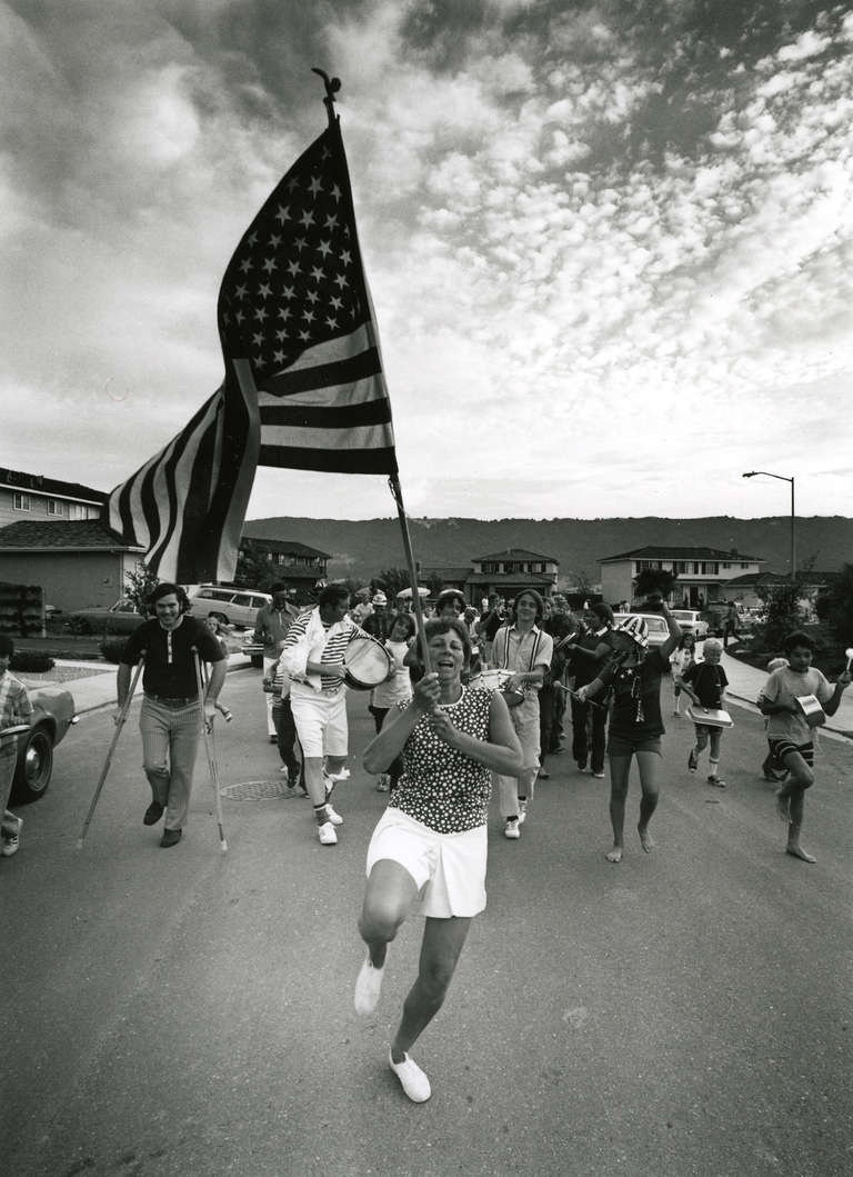 Bill Owens Figurative Photograph – Paradefrau mit amerikanischer Flagge, aus Suburbia