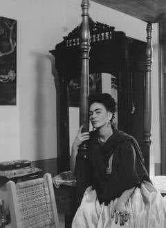 Frida Kahlo Sitting on Bed, Arm Around Bedpost