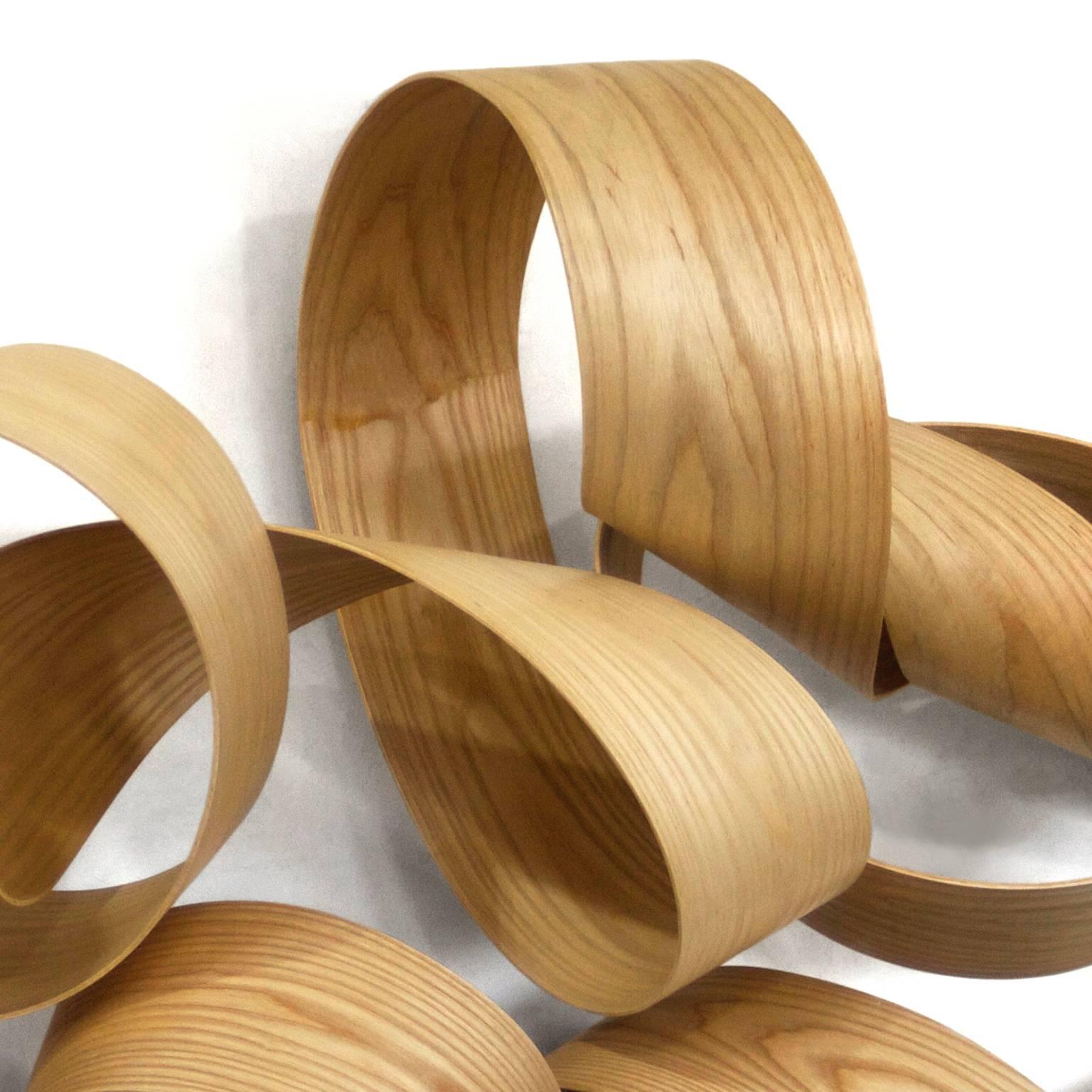 A beautiful ribbon of natural wood this wall mounted sculpture is contemporary yet lyrical and compliments a variety of decors. Sculptor Jeremy Holmes' curving twisting creations range in scale from modestly sized free standing sculptures to gravity