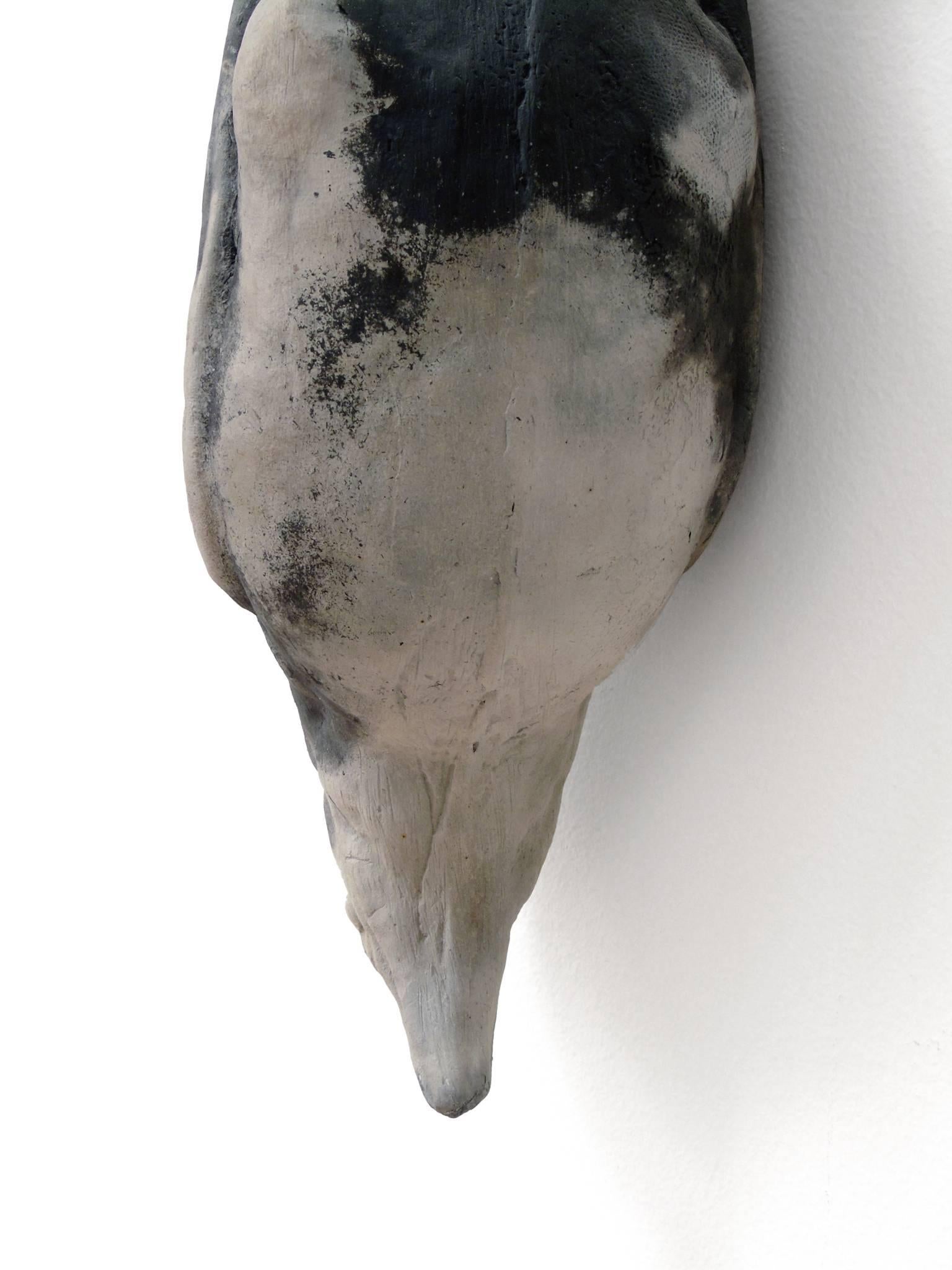 Messenger is a raku fired clay crow that hangs from a large nail. It is suspended below rolled paper notes that have been dipped in beeswax from artist Michael Roger's hives. The handwritten text on the paper is from poetry by Forrest Gander.