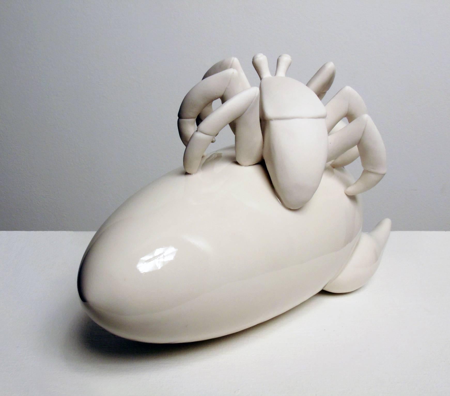 Starter Pet Adaptation in white porcelain by Bethany Krull features a stylized crab on a sideways rocket ship. Like much of Krull's creative output this piece speaks to the complicated and often contradictory relationships humans maintain with other