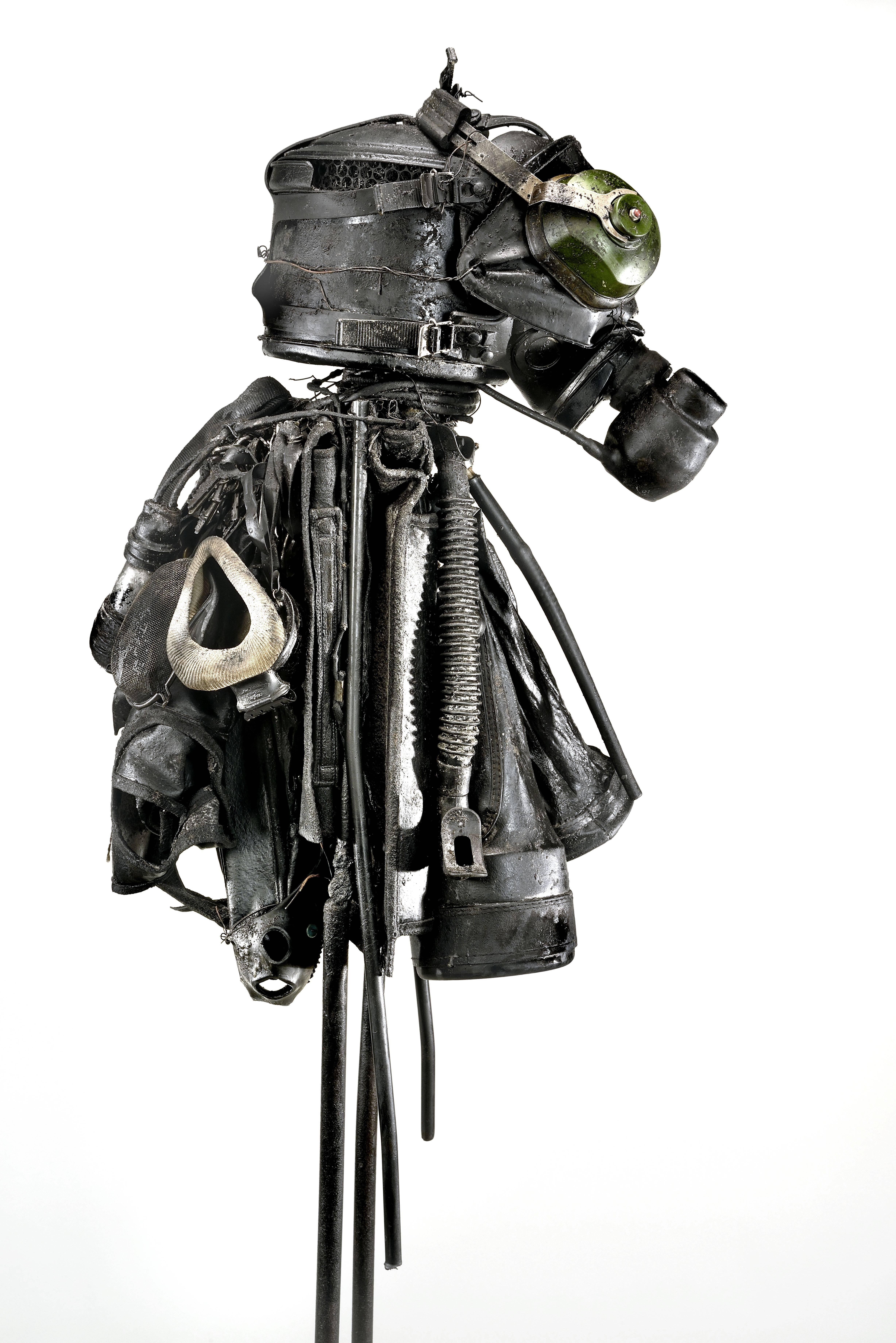 "Bug" is one of artist Ronald Gonzalez' Black Figures. At its core it is a rudimentary representation of a human, a stick figure constructed of steel rod. A dark conglomeration of artifacts make up its flesh: headphones, golf bag, snorkel,
