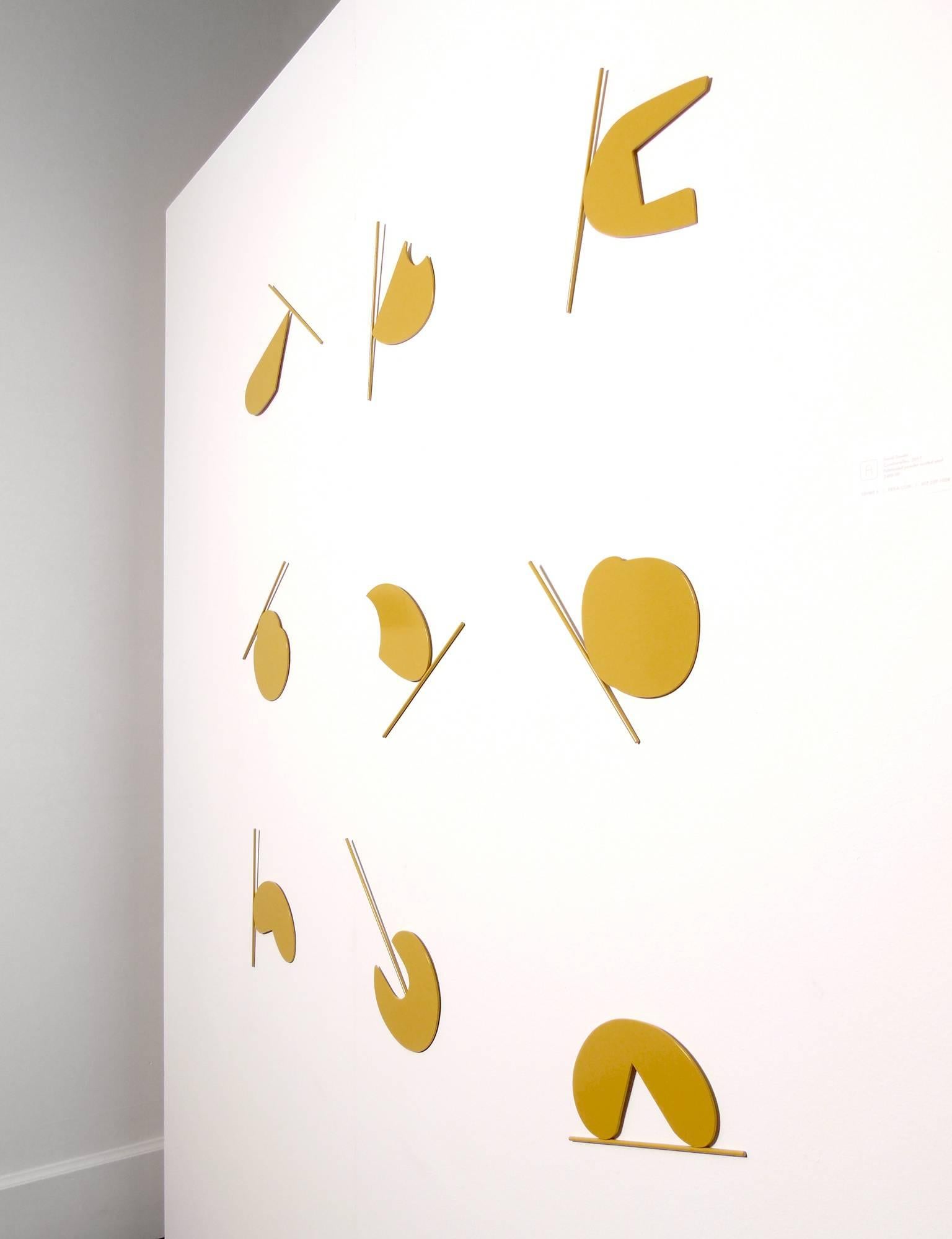 Combarelles by David Dowler is made up of nine cut steel shapes in a deep, almost ochre yellow. It is a modular wall mounted sculpture that looks almost two-dimensional at first glance. Its graphic look and color have a bold unique look. The 1/8