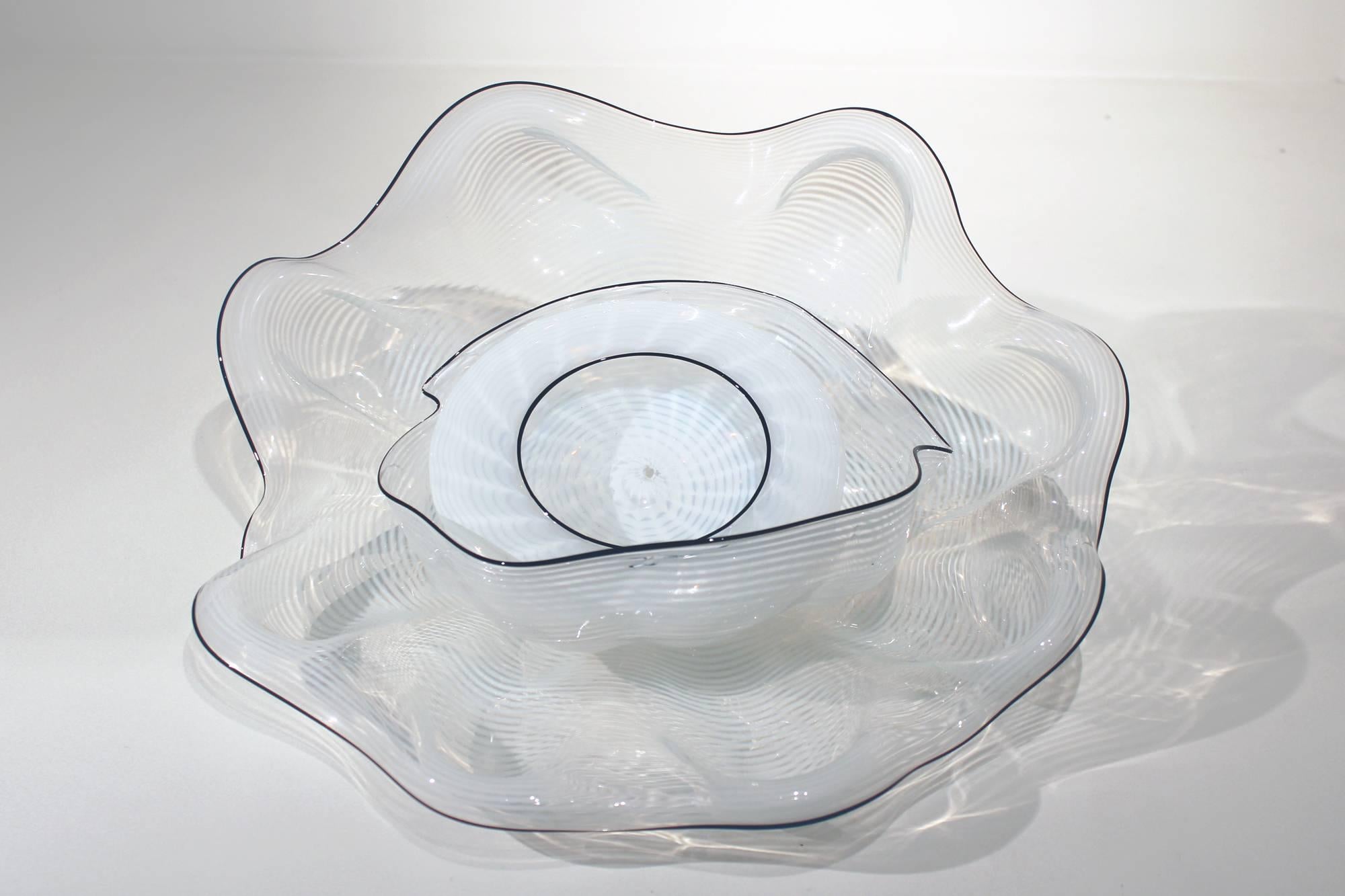 This unique White Seaform with Black Lip Wraps was created by renowned artist Dale Chihuly in 1986. It is comprised of three elements, is signed and dated. 
The Basket series metamorphosed into Seaforms in 1980. More delicate, thin-walled, and made