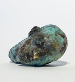 Scultura di una testa-amuleto in bronzo in formato tascabile con patina di verdigris