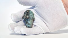 Scultura di una testa-amuleto in bronzo in formato tascabile con patina di verdigris