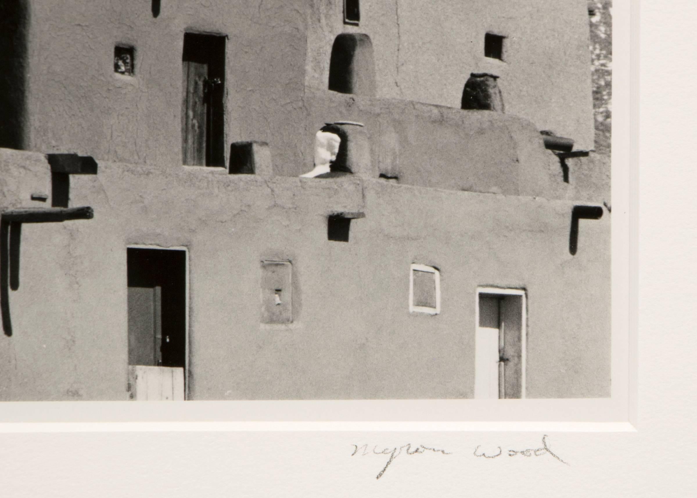 This original signed black and white photograph by renowned photographer Myron Wood (1921-1999) beautifully captures the historic Taos Pueblo in New Mexico during winter. Showcasing the iconic adobe dwellings set against snow-covered mountains, this