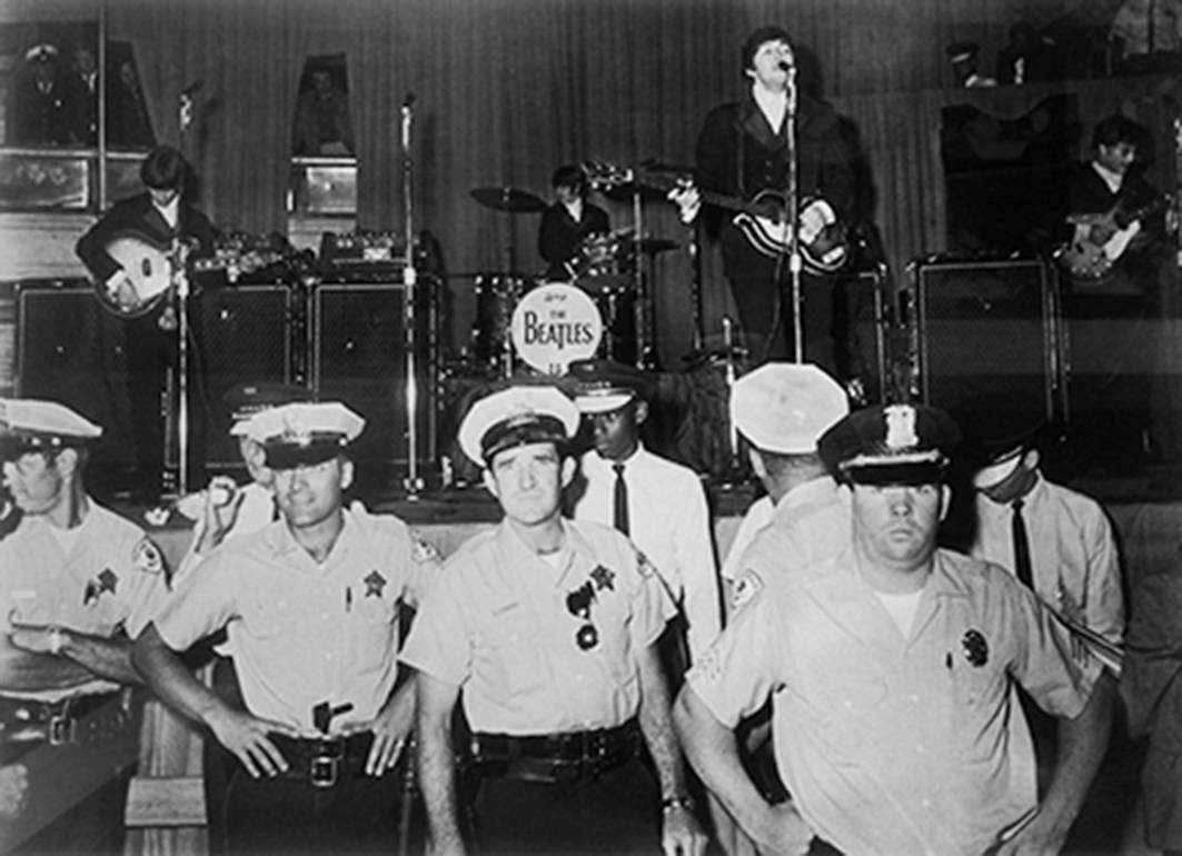 Black and White Photograph di Harry Benson - The Beatles sul palco (con poliziotti), Chicago, 1966