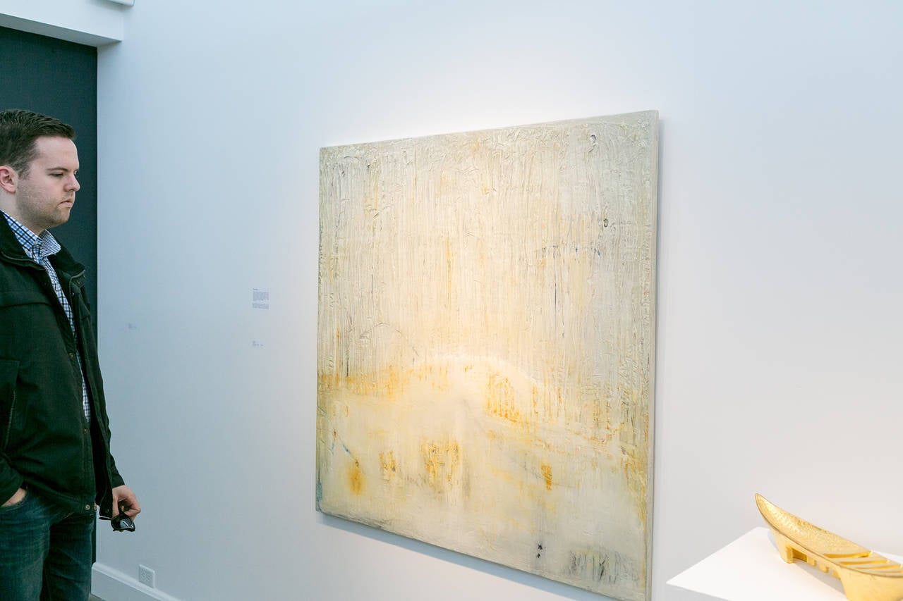 Abstracted textured landscape in soft white and gold. 

Naim’s large-scale abstract paintings are monochromatic, tactile, and highly personal in nature. Working with plaster on wood, Naim opts to use her hands to apply ink, chalk, charcoal,