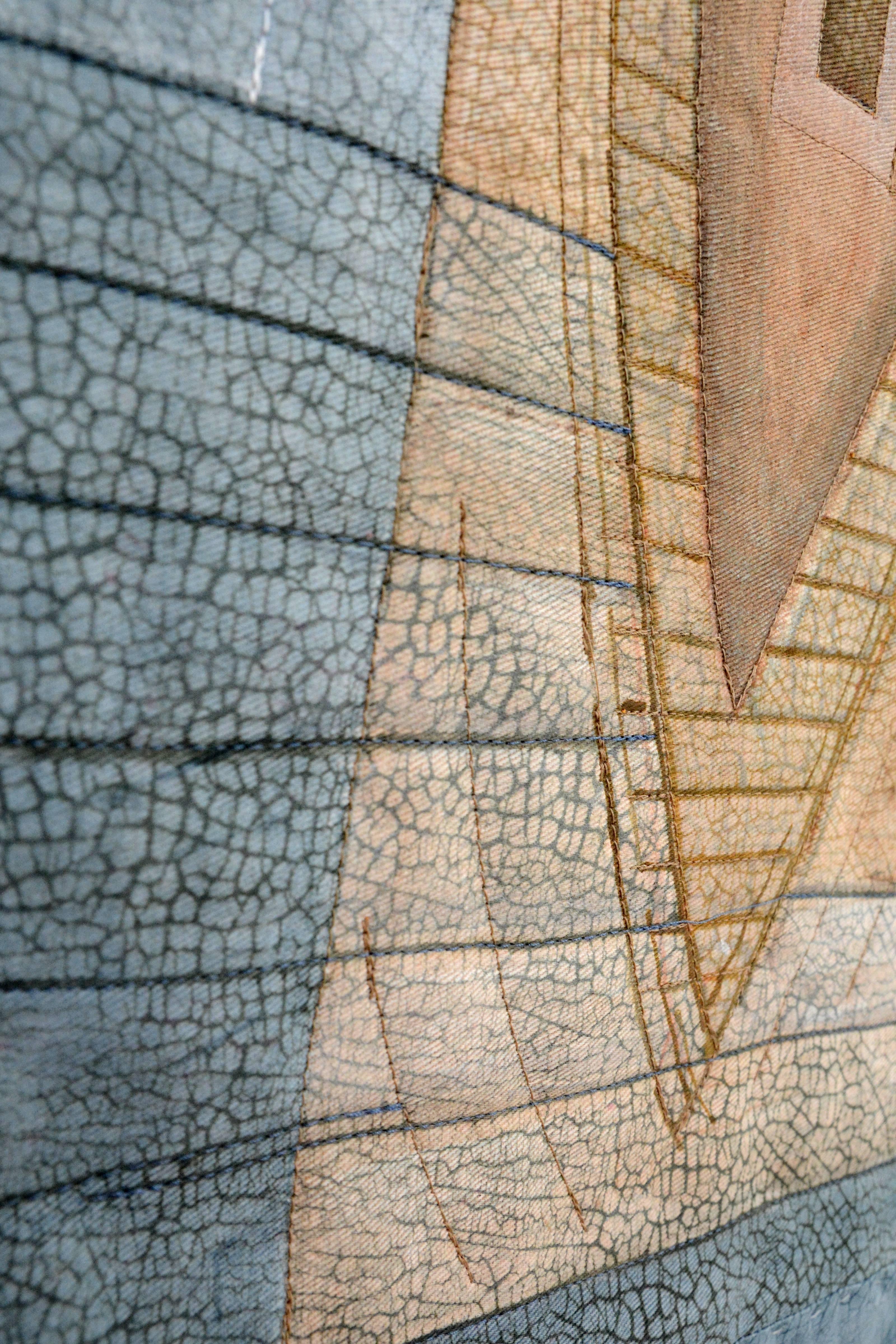 Une forme de canoë en céramique perforée et marquée émerge d'un socle à côté d'une tapisserie de bleu et de brun clair qui répète la forme verticale du canoë. Le titre de cette œuvre en techniques mixtes peut faire référence à la collecte