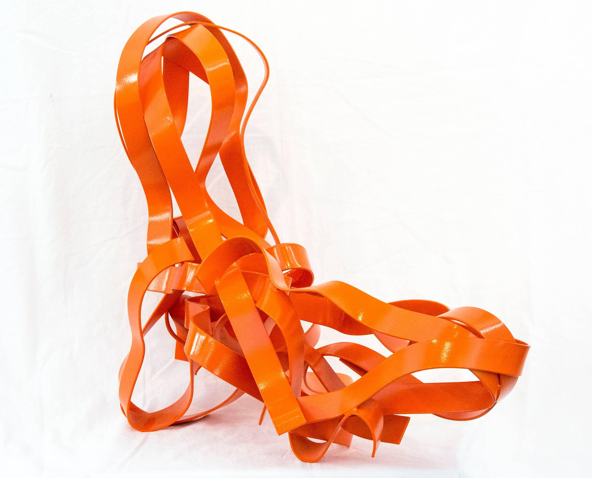 Ribbons of glossy, bright orange steel follow circuitous paths that unwind and intersect gracefully in this abstracted shape of a reclining figure. 

The seeming effortlessness of the flowing ribbons is belied by the physical process of making this