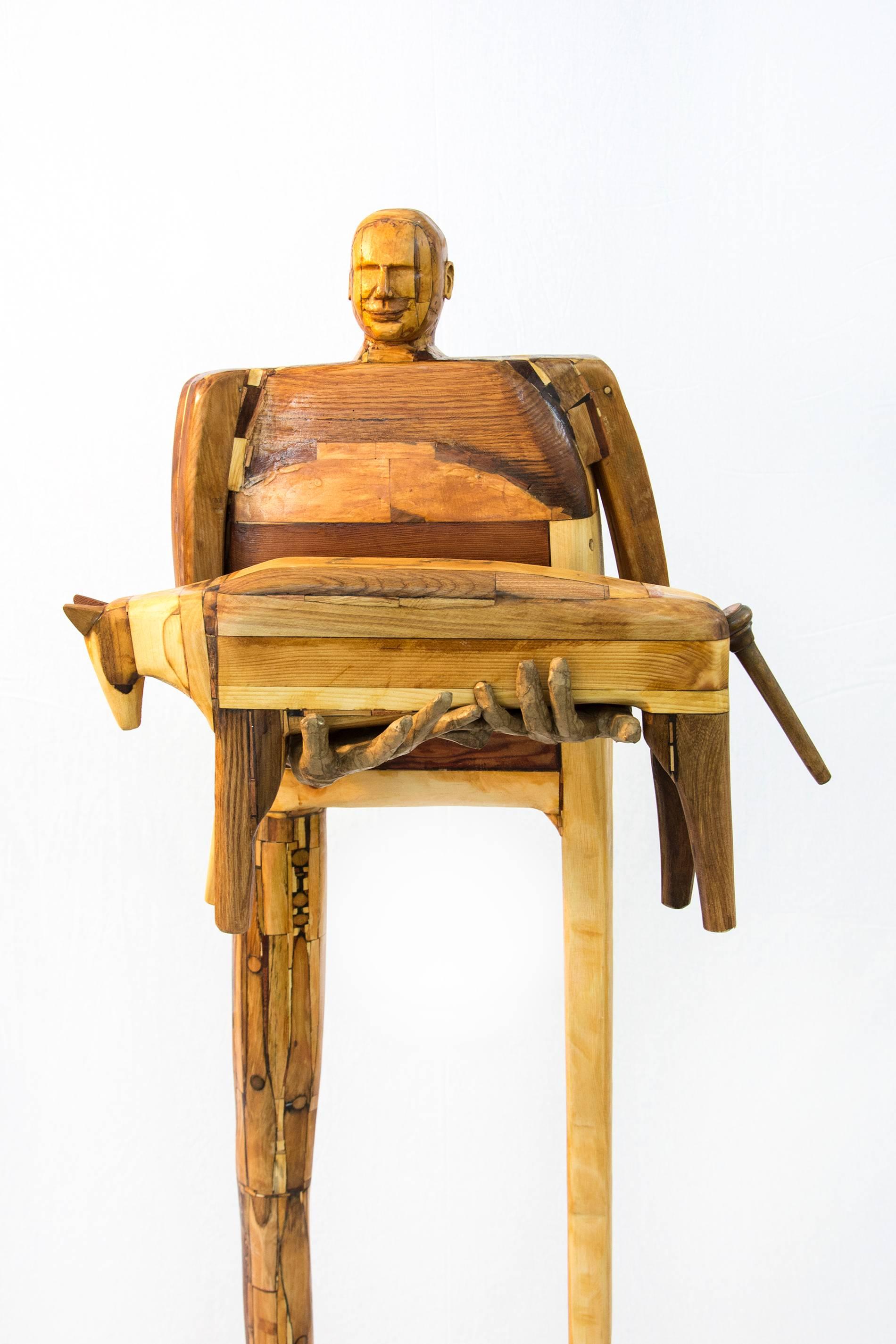 Reclaimed wood figure holding a pet dog. The dog can be lifted out of the figures hands. This sculpture is created out of reclaimed chairs, wood and found objects painstakingly layered with resin.

