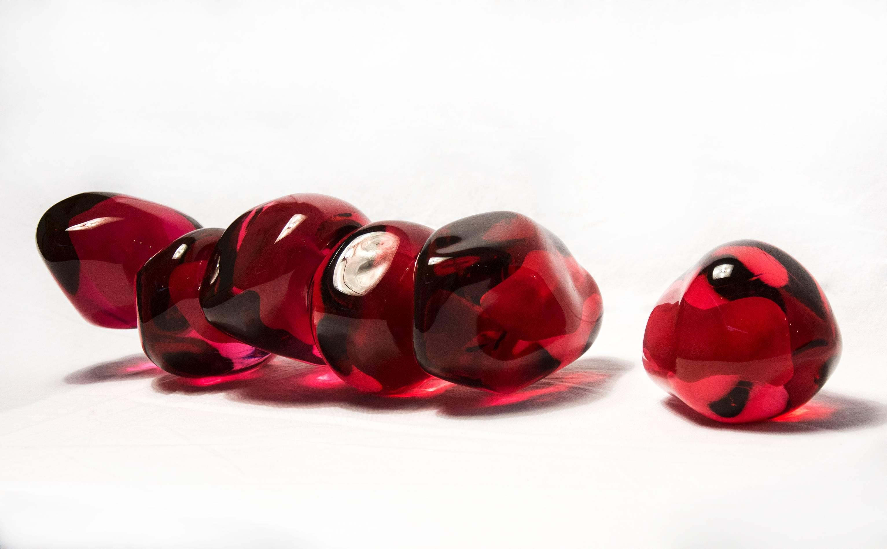 Die länglichen, sinnlichen Formen aus durchscheinendem, rotem Glas haben eine glatte, geschliffene Oberfläche wie die Frucht, die den Granatapfelkern umgibt. Ein einzelnes Samenkorn sitzt neben dem Cluster. Der Granatapfel steht für Reichtum, Glück