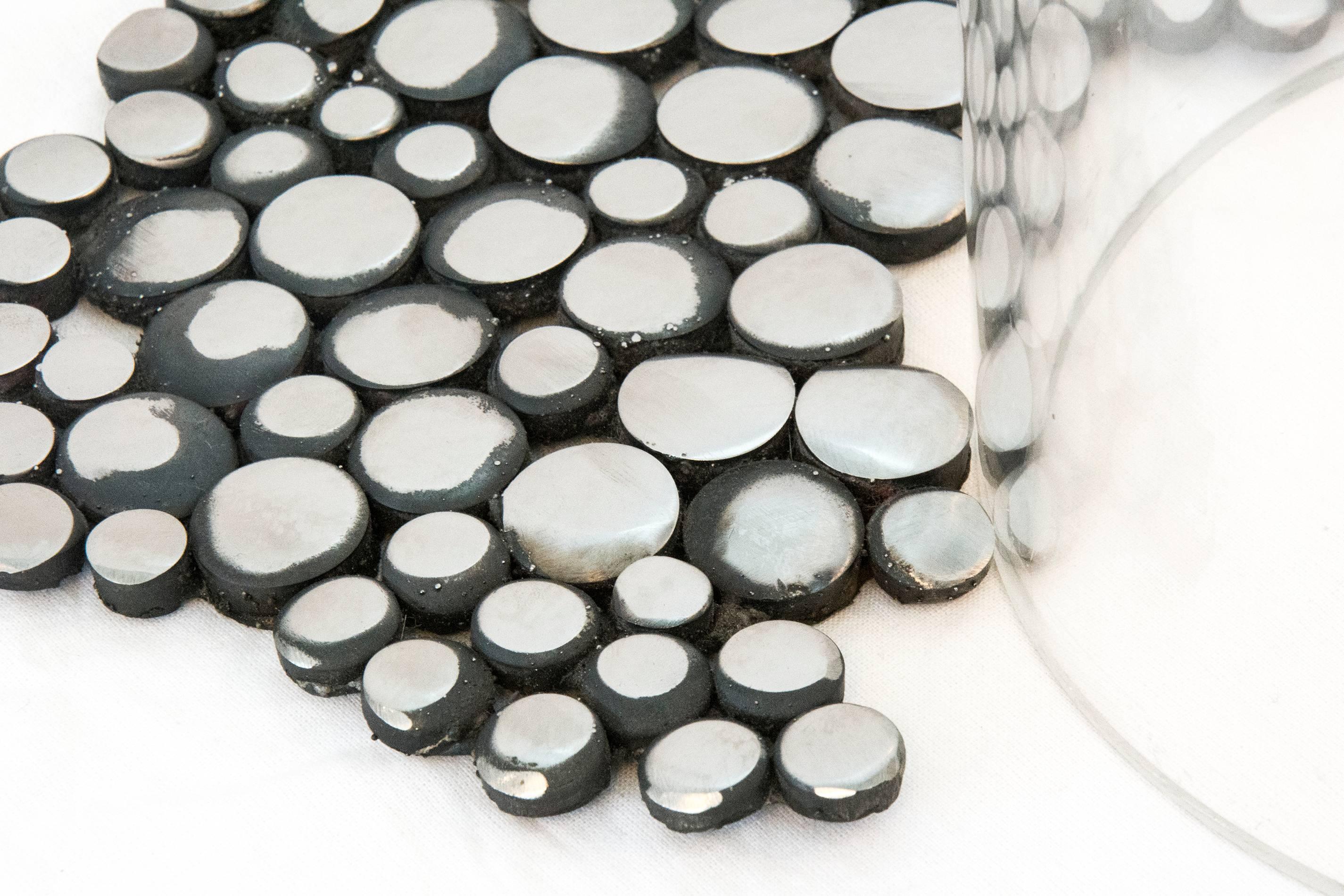 Composée de nombreux petits disques en acier inoxydable, une tête creuse flottant sur un cylindre en plexiglas transparent semble fondre, les disques diminuant de taille et formant des 