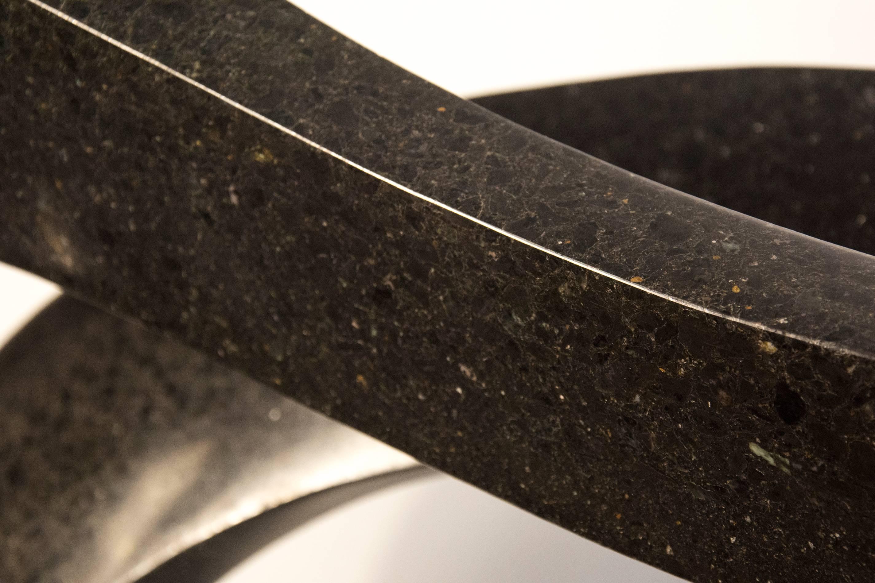Smooth surfaced, black granite flecked almost imperceptibly with copper and white has been engineered into an elegant ribbon in tangible contrast to its weight.  This work has a steel substructure and sits on an aluminum base. The work is aptly